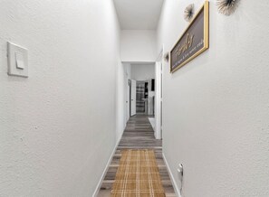 Ein Flur mit Holzboden, weißen Wänden, einem Teppich und einem gerahmten Schild.
