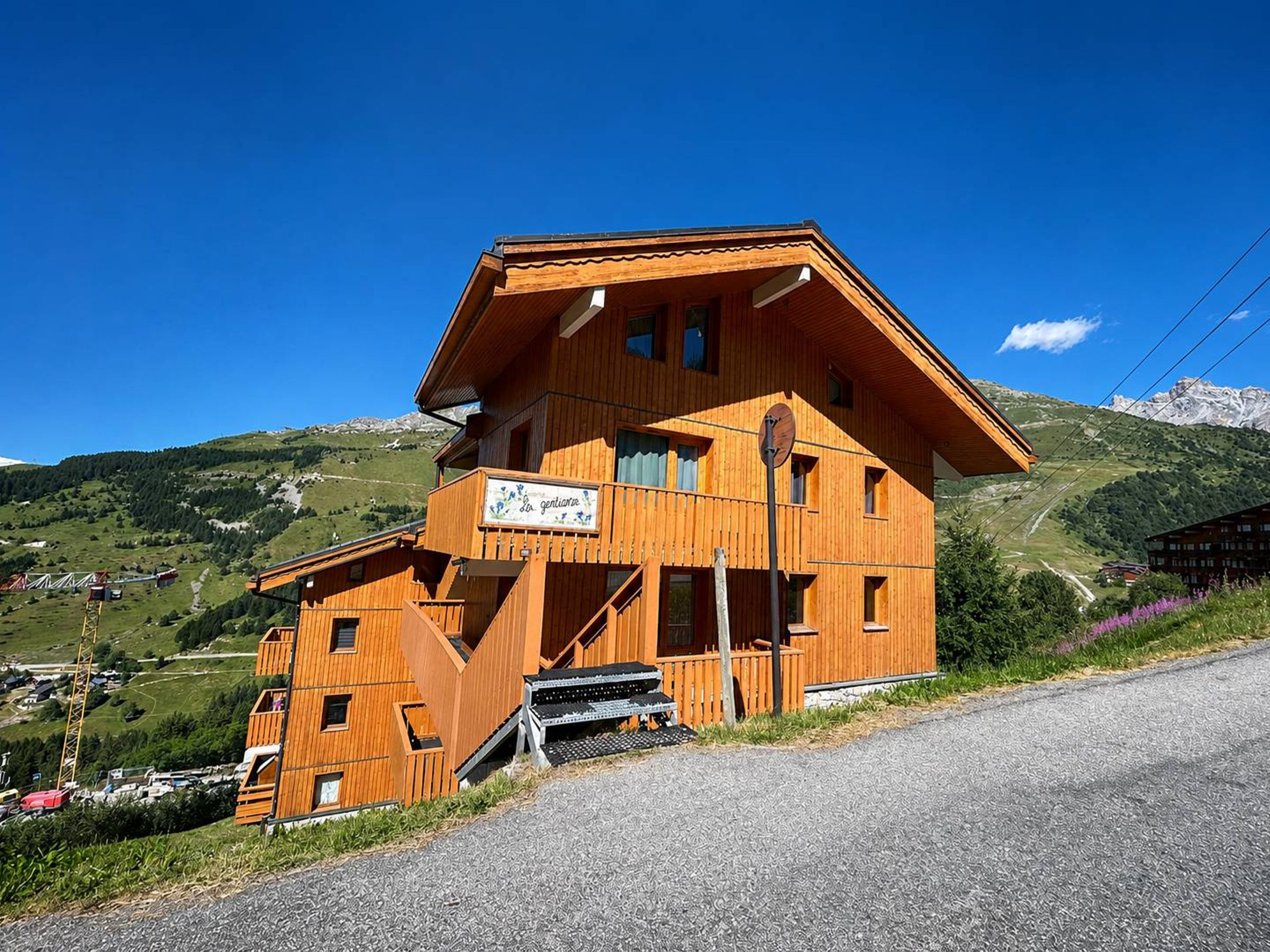 Eine Holzchalet mit Balkon, einem Schild mit der Aufschrift 'Hotel Gentilhomme' und einer Bergkulisse.