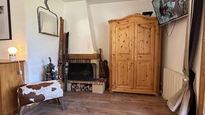 A living room with a fireplace, wooden furniture, a television, and a Christmas tree. - Spacious duplex, mountain view - 5 guests (Méribel)