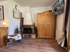 A living room with a fireplace, wooden furniture, a television, and a Christmas tree. - Spacious duplex, mountain view - 5 guests (Méribel)