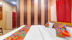 A hotel room with a bed, a wooden wardrobe, and a red curtain. - Hotel Shree Ram Adhar (Ayodhya)