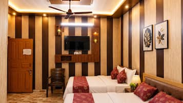 A hotel room with two beds, a ceiling fan, a TV mounted on the wall, and a wooden door.