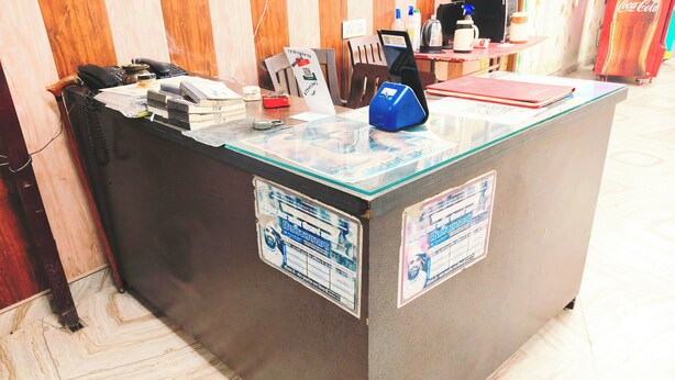 Una recepció amb taulell de vidre, un dispositiu blau i cartells informatius.