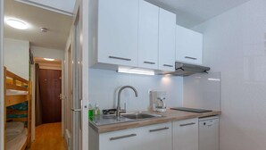 A compact kitchen with white cabinets, a stainless steel sink, and a coffee maker. - Comfortable central studio - 4 guests (Barèges)