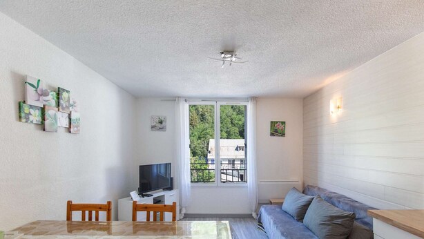 A compact living space with a dining table, chairs, a sofa, a TV, and artwork on the walls. - Comfortable central studio - 4 guests (Barèges)