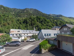 Ein Hotel mit Parkplatz, Gebäude mit geneigten Dächern und einer Bergkulisse.