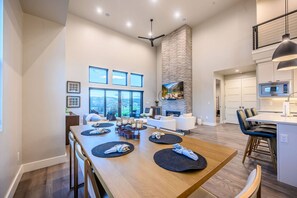 A spacious living area with a fireplace, large windows, and a dining table set with placemats and napkins. - Labor Day Sale - Limited Time Offer, Save up to 30% (Daniel)