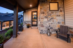 A covered porch with a stone wall, a bench, and a door leading to a house. - Labor Day Sale - Limited Time Offer, Save up to 30% (Daniel)