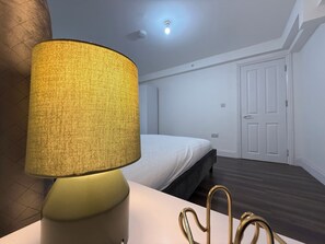 A room with a bed, a lamp, and a door. - Amazing Huge 5 Bed / 10 Sleeper in London Zone 2. (London)