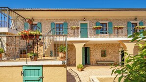 A two-story building with stone walls, green shutters, and balconies with potted plants. - Villa Dalmatia Luxury Stone Villa With Pool & Tennis (Sveti Filip i Jakov)