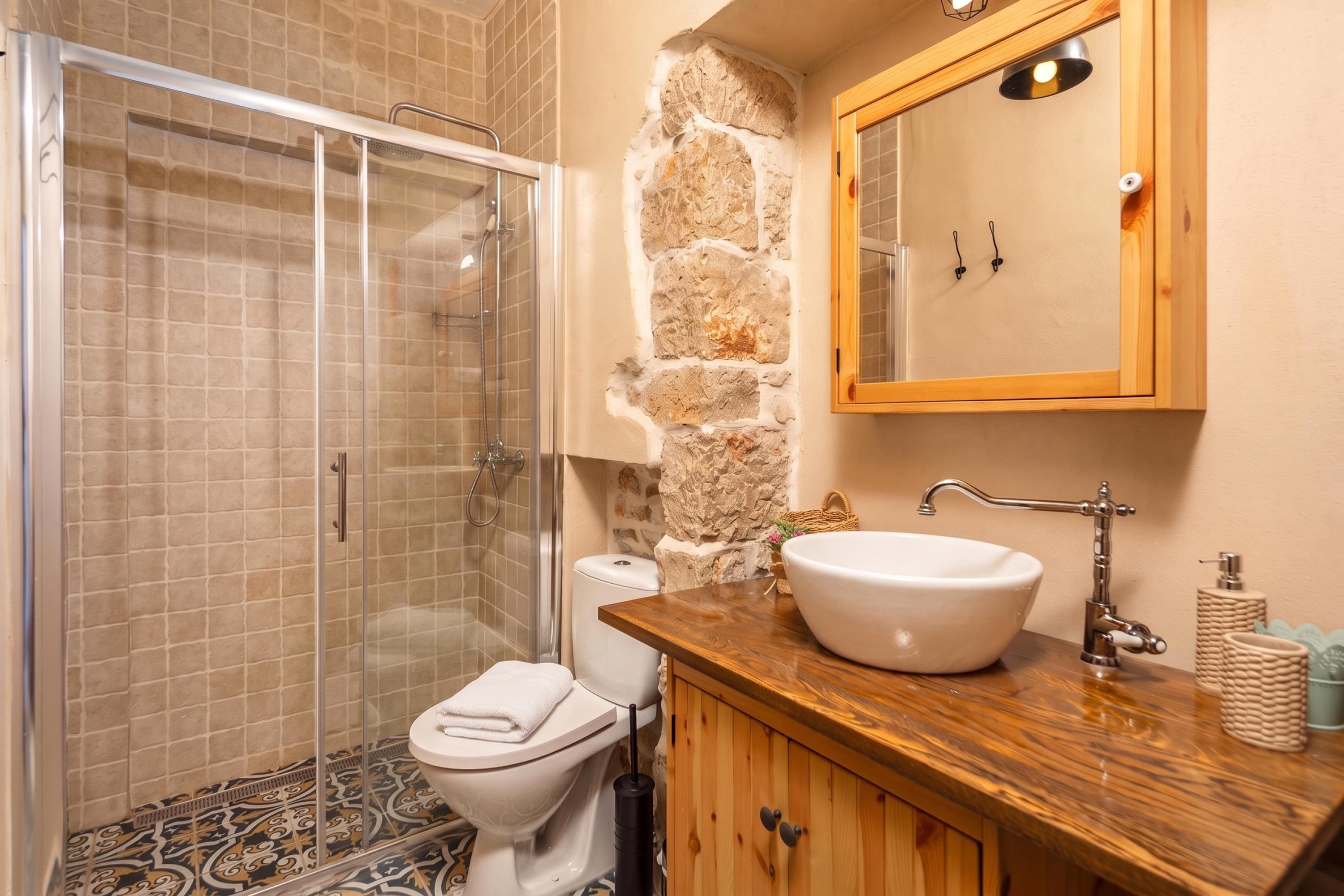 Ein Badezimmer mit einer Duschkabine, einer Toilette und einem Holzkosmetikschrank mit Waschbecken.