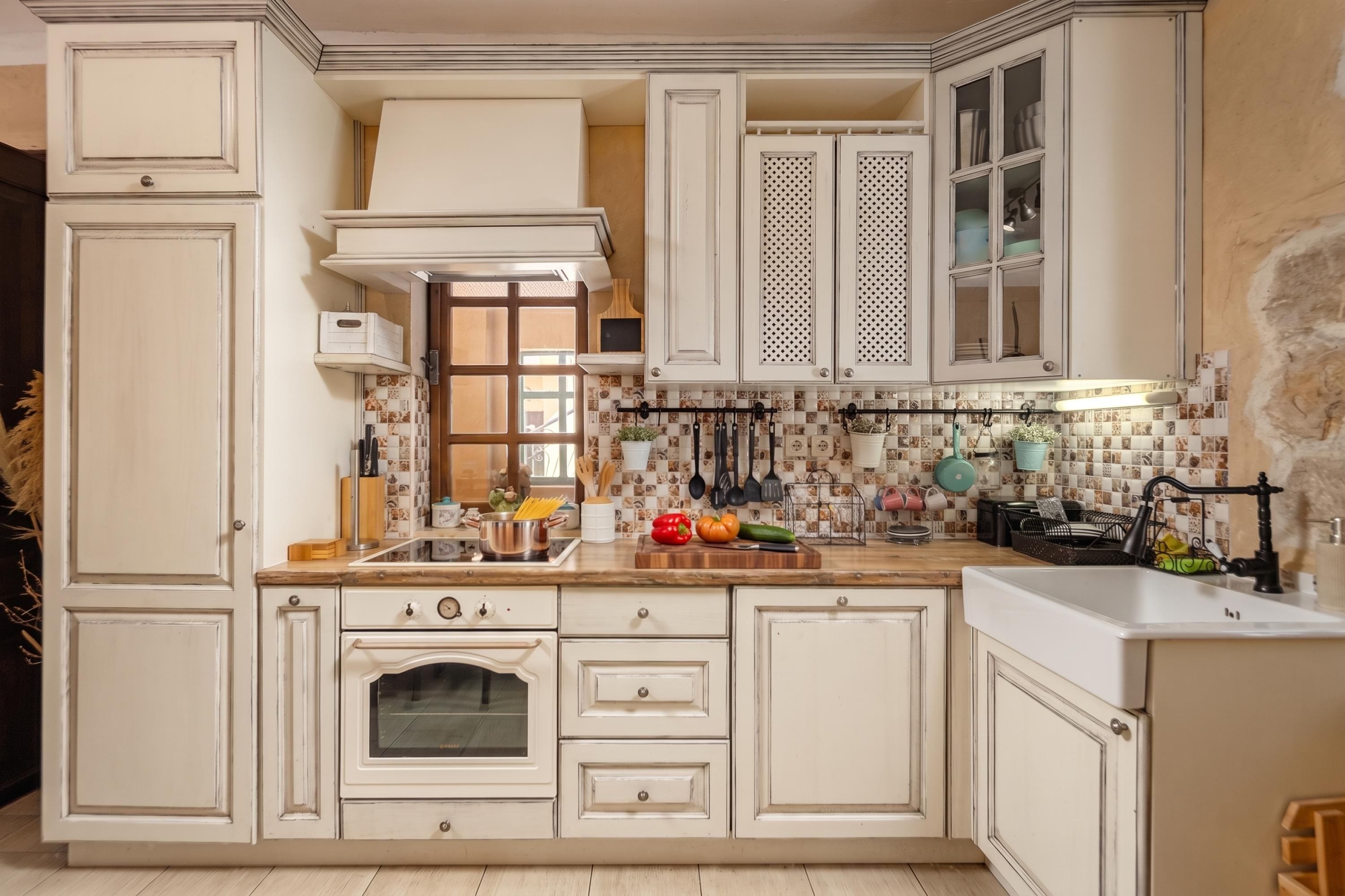 A kitchen with white cabinetry, a stove, and a tiled backsplash.