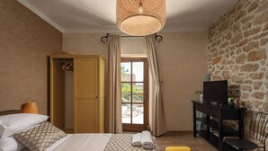 A bedroom with a bed, a wardrobe, a television on a stand, and a stone wall. - Villa Dalmatia Luxury Stone Villa With Pool & Tennis (Sveti Filip i Jakov)