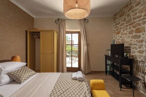 Ein Schlafzimmer mit einem Bett, einem Kleiderschrank, einem Fernseher auf einem Schrank und einer Steinwand.