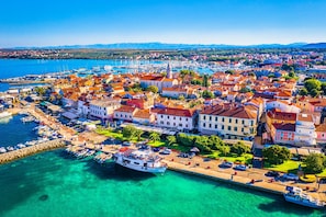 A coastal town with a marina, buildings with red-tiled roofs, and clear turquoise waters. - Villa Dalmatia Luxury Stone Villa With Pool & Tennis (Sveti Filip i Jakov)
