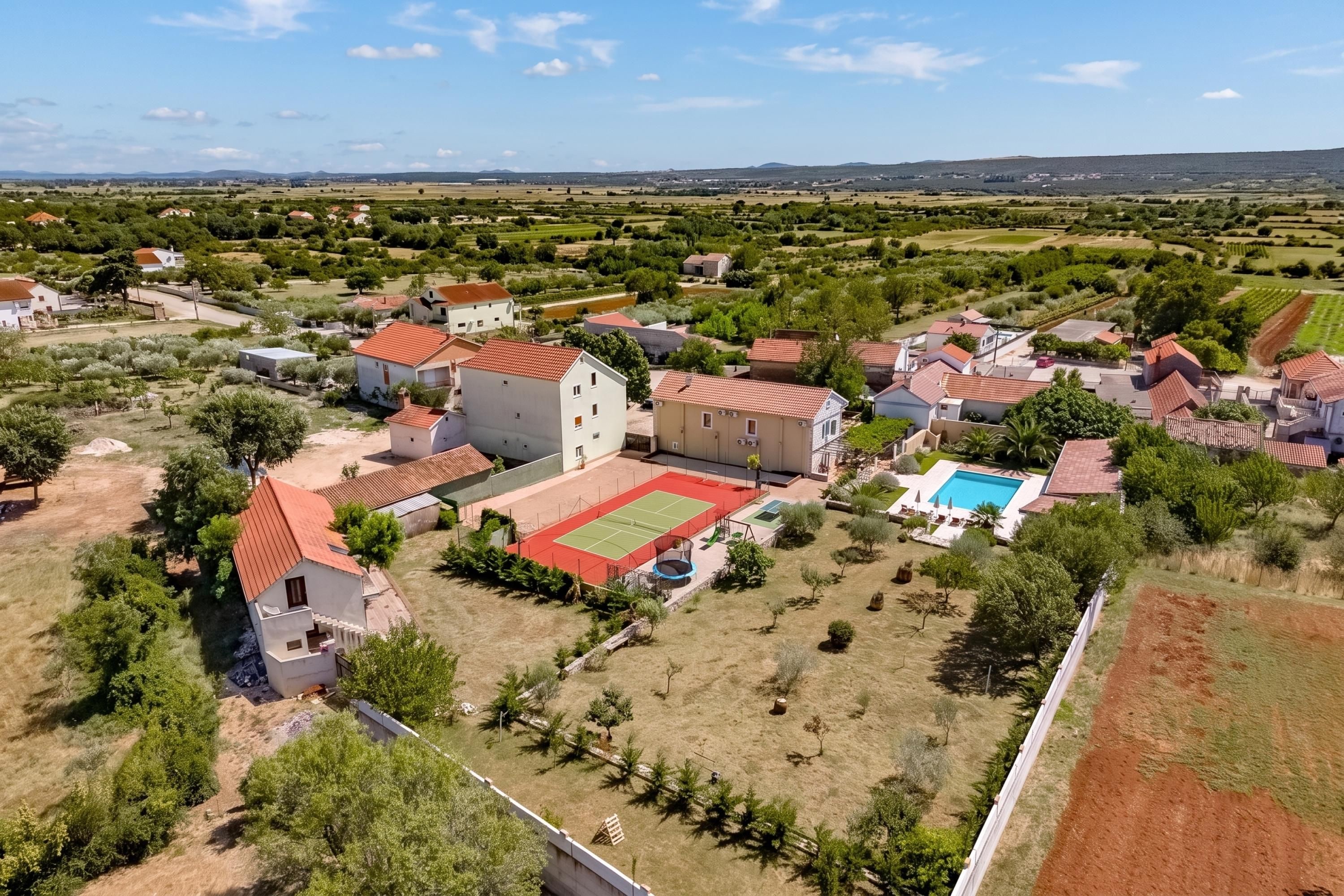 A residential area with houses, a tennis court, and a swimming pool.