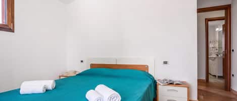 A bedroom with a bed, a nightstand, a mirror, and a door leading to a bathroom.