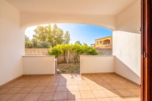 Ein offener Balkon mit Blick auf einen Garten und ein Gebäude.