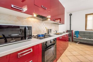 Eine moderne Küche mit roten Schränken, einer eingebauten Mikrowelle, einem Gasherd und einem Edelstahlbackofen.