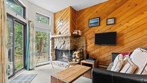 A cozy living room with a stone fireplace, a flat-screen TV, and a comfortable sofa.
