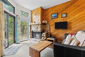 A cozy living room with a stone fireplace, a flat-screen TV, and a comfortable sofa.