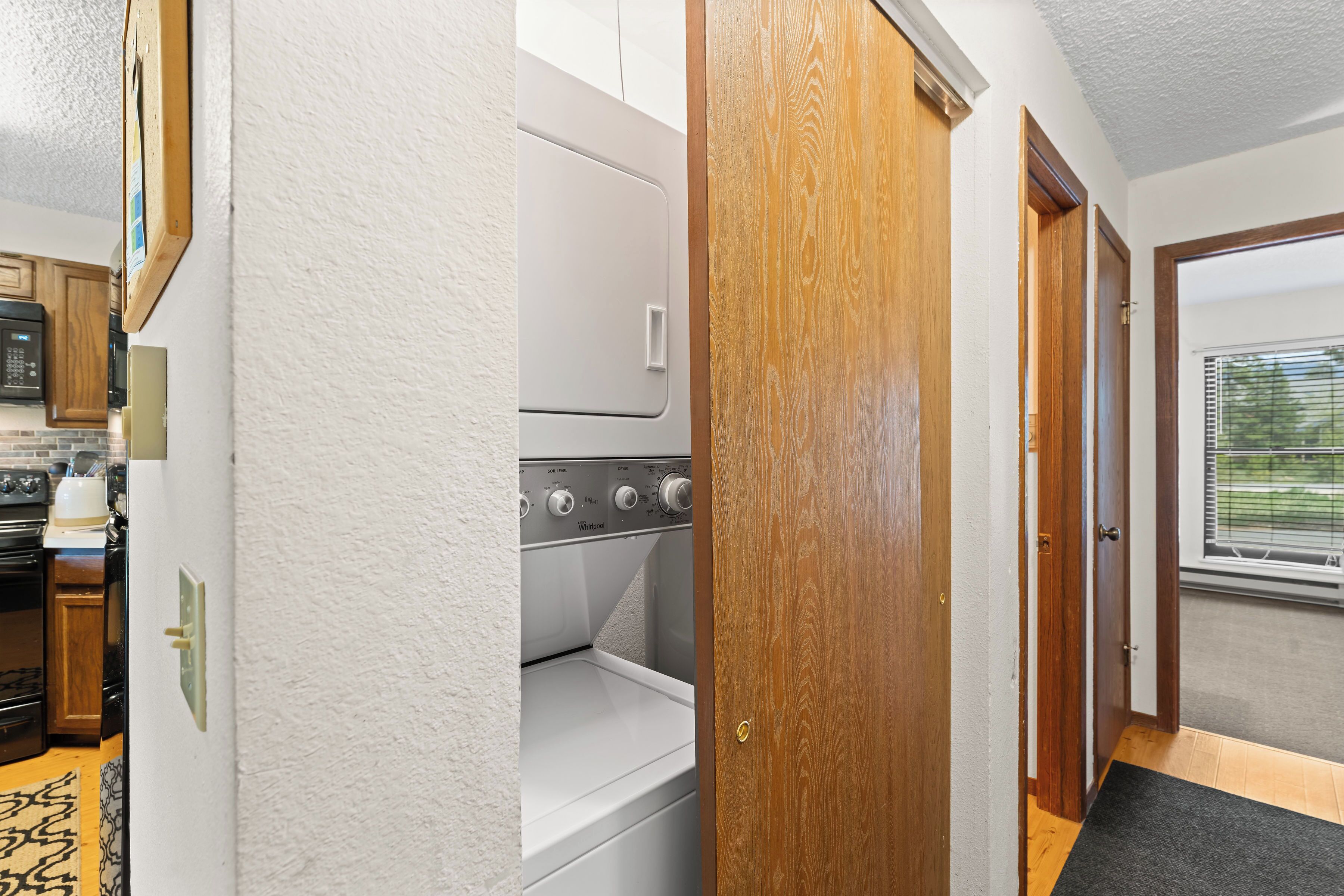 A laundry room with a washer and dryer, wooden doors, and a view of the outside through a window.