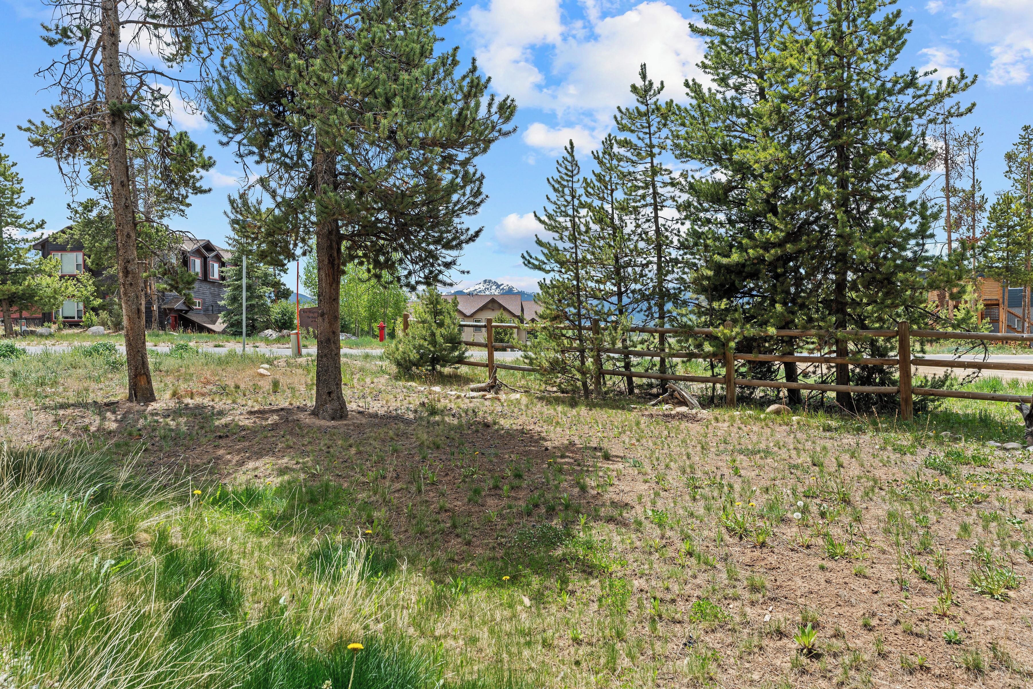 A natural landscape with trees, a wooden fence, and a building in the background.