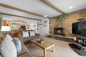 A living room with a stone fireplace, a television, and a sofa. - Hi Country Haus Unit 2301 Spacious 2 bed, ground floor, walk to downtown (Winter Park)