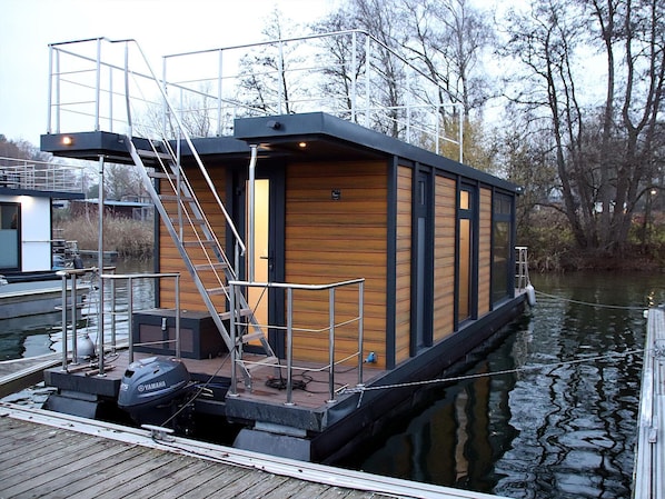 A houseboat docked at a pier with a staircase leading to the entrance.