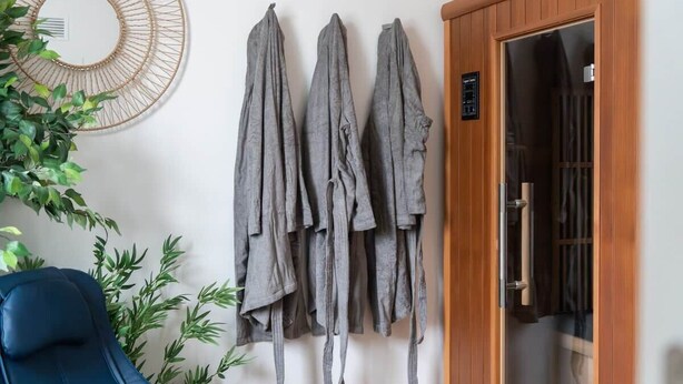 Una habitación con una silla azul, un tendedero fijado a la pared y una puerta de madera.