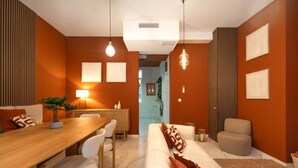 Una sala moderna con una mesa de comedor de madera, sofás blancos y un amplio ventanal.