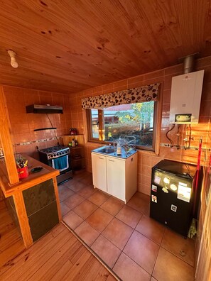 Una cucina compatta con una finestra, una stufa, un lavello e un frigorifero.