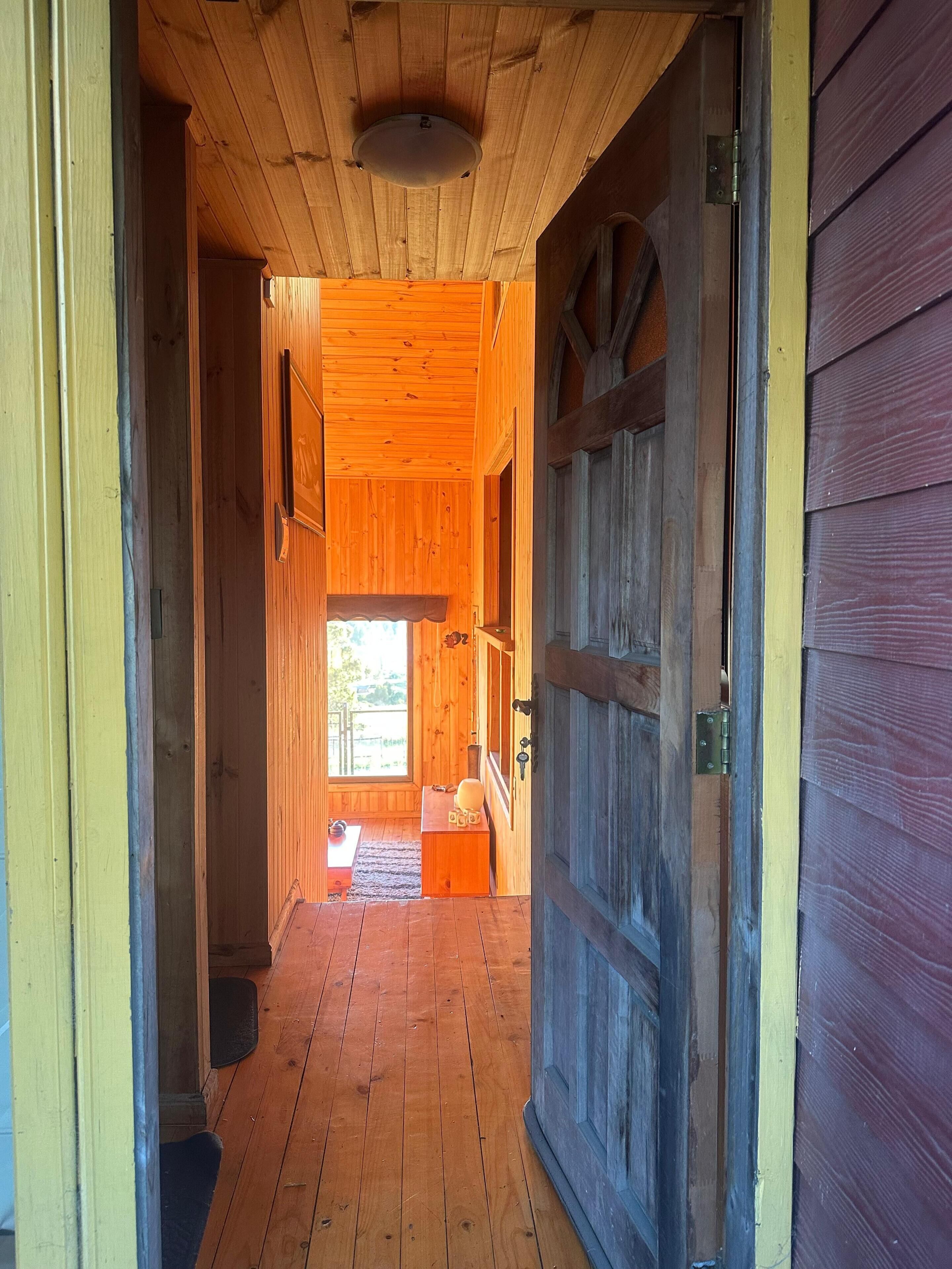 Un couloir intérieur en bois qui mène à une porte dotée d’une fenêtre.