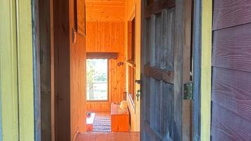 Un couloir intérieur en bois qui mène à une porte dotée d’une fenêtre.