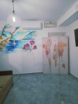 A room with a marble floor, a wall-mounted air conditioner, a globe map, and a hanging light fixture. - Erminia Apartaments (Vico Equense)