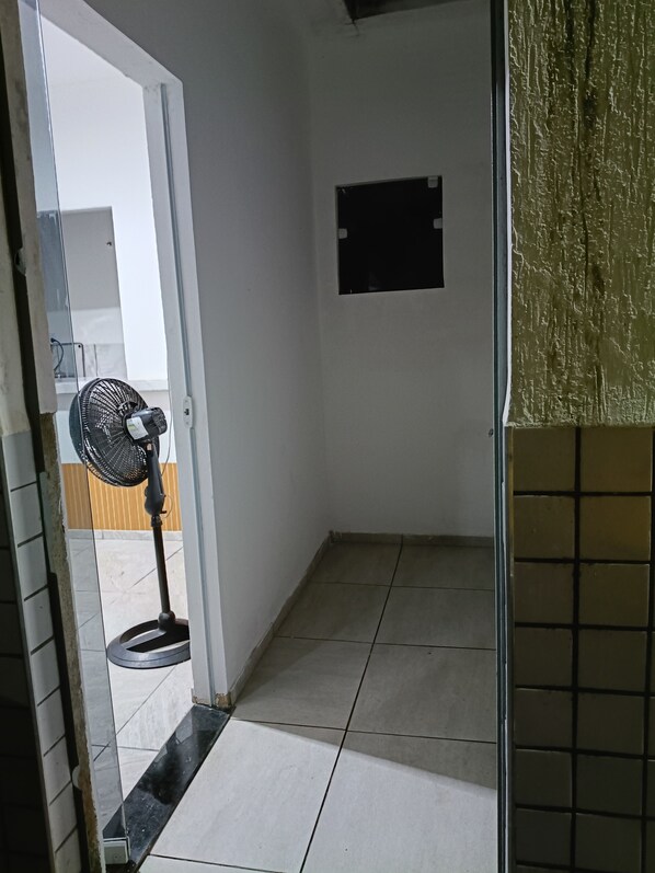 A room with a tiled floor, a standing fan, and a blackboard on the wall.