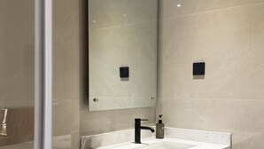 Une salle de bain avec un lavabo en marbre blanc, un robinet noir et un miroir au-dessus.
