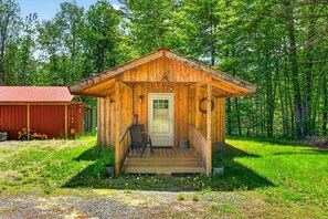 A wooden cabin with a porch, a door, and a small table with chairs. - Soothing 1-bedroom COTTAGE with AC in charming Topsham (Topsham)