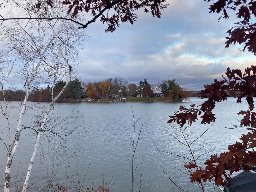 Ein See mit einem Haus im Hintergrund, umgeben von Bäumen.
