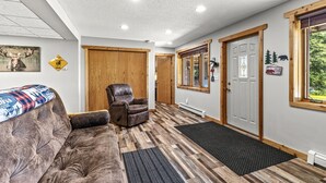 Una sala de estar acogedora con un sofá marrón, un sillón de cuero y piso de madera.
