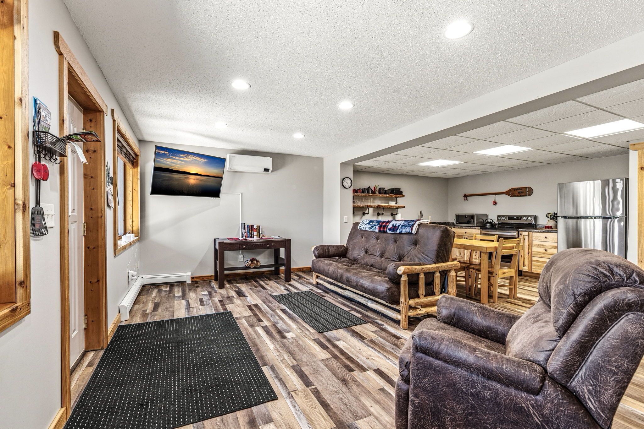 A cozy living room with a sofa, armchairs, a coffee table, and a TV mounted on the wall.