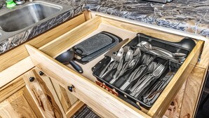 Un cajón de cocina con utensilios y un rallador.