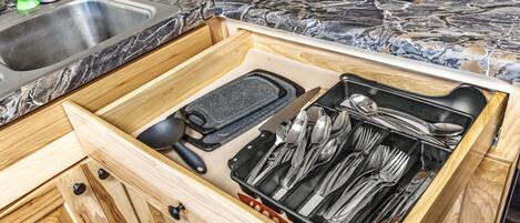 A kitchen drawer with utensils and a grater.