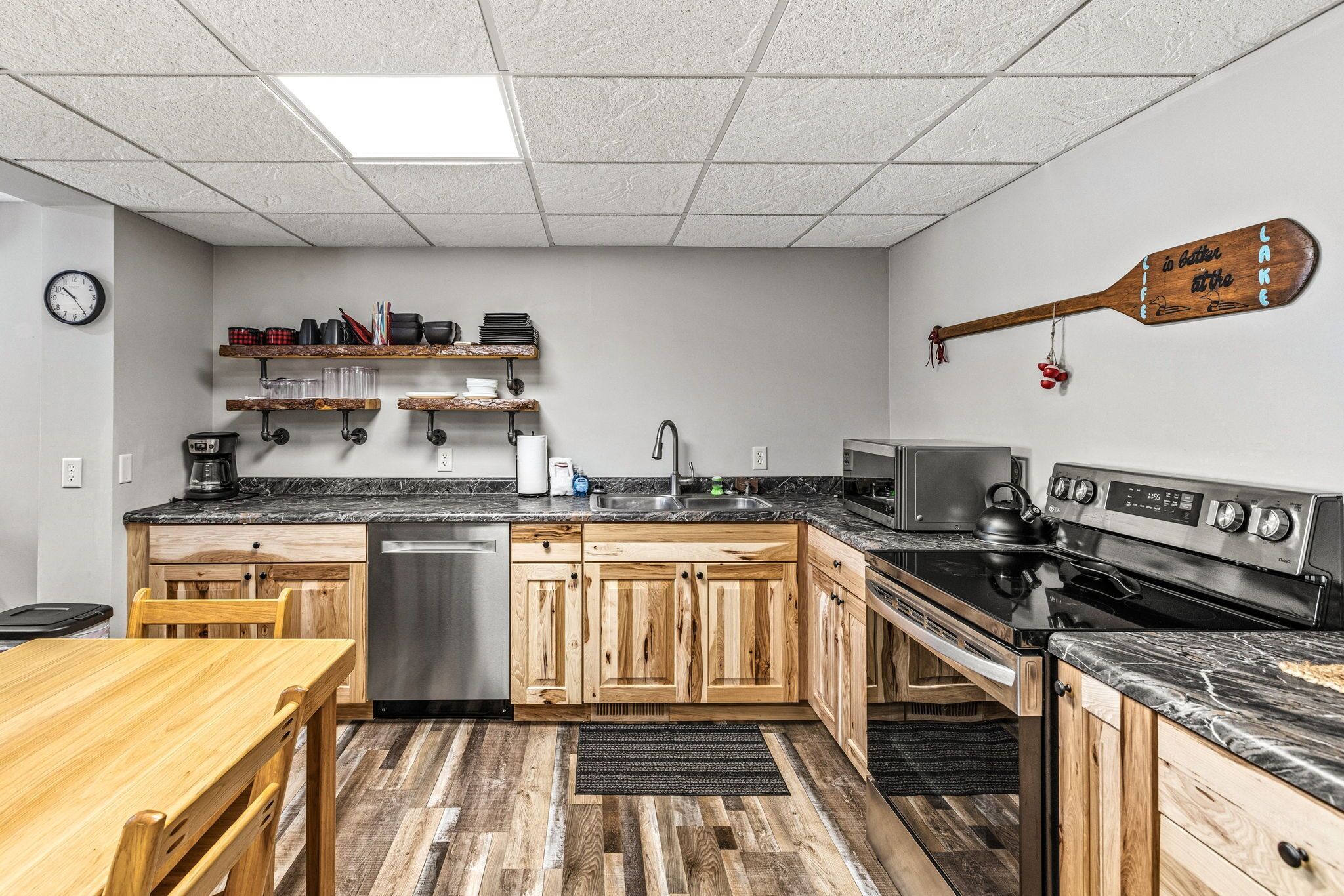 A kitchen with wooden cabinets, a stainless steel refrigerator, a microwave, a stove, and a coffee maker.