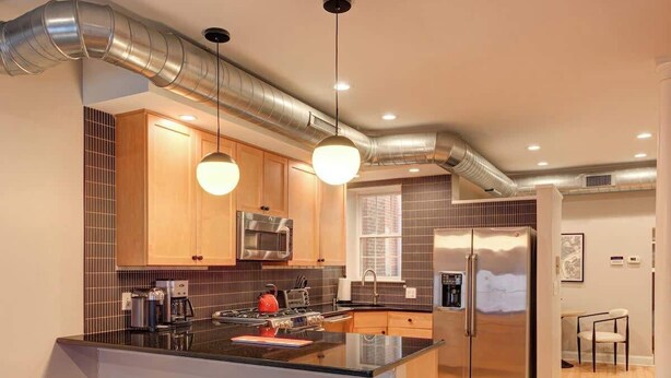 Una cocina moderna con una isla central, electrodomésticos de acero inoxidable y taburetes de bar.