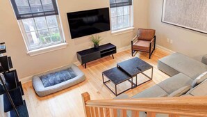 Una sala de estar moderna con una televisión de pantalla plana, un sofá, una mesa de centro y un sillón.
