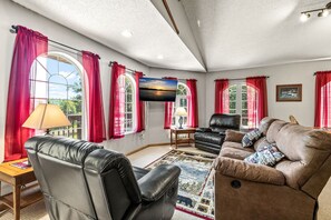 A living room with leather sofas, a flat-screen TV, and red curtains. - Long Lake Landing – Unit 3 | Spacious Lakeview Condo with Private Boat Slip (Sarona)