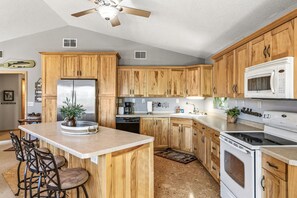 A kitchen with wooden cabinets, a refrigerator, a microwave, and a stove. - Long Lake Landing – Unit 3 | Spacious Lakeview Condo with Private Boat Slip (Sarona)