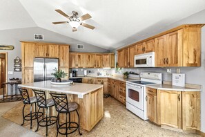 A kitchen with wooden cabinets, a stainless steel refrigerator, a microwave, a stove, and a ceiling fan. - Long Lake Landing – Unit 3 | Spacious Lakeview Condo with Private Boat Slip (Sarona)