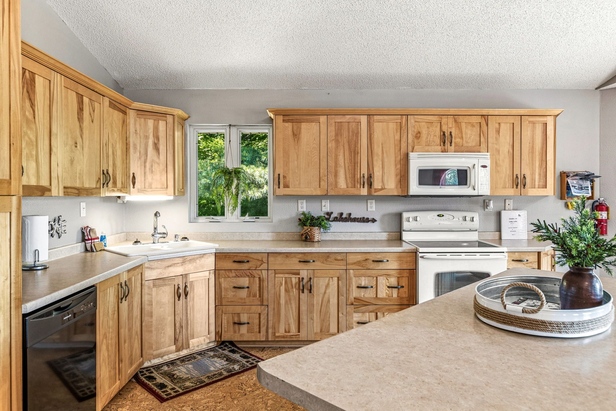 Una cocina con armarios de madera, microondas, estufa y pileta.